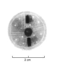FIB-5330 - Fibule discoïde en forme de boucliercuivreTôle circulaire avec un besant centra, d'où partent des lignes gravées formant des rayons (4 à 6 groupes) séparant des ocelles poinçonnés.