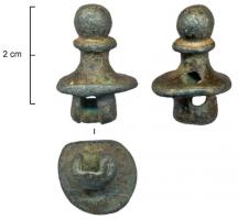 IND-4028 - Objet indéterminébronzeSorte d'embout à collerette, bouleté au sommet ; un trou carré perfore la base en oblique jusqu'au dessus de la collerette