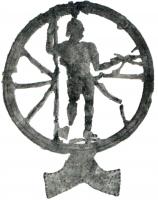 IND-4328 - Enseigne ou applique : Jupiter, roueplombEnseigne ou décor d'applique montrant Juiter-Taranis debout, nu, appuyé sur sa lance à droite et tenant le foudre dans la main gauche, au centre d'une roue posée sur un motif en forme d'accolade ou de moustache.