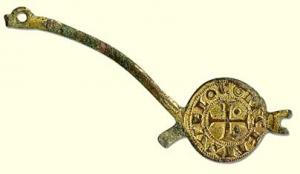 IND-6008 - Armature à décor monétiformebronze doréObjet avec motifs monétiformes (deniers languedociens des XIIe-XIIIe s.), disposés sur une tige bifide, une ou deux branches interrompues par des bélières.