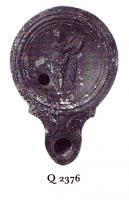 LMP-41058 - Lampe Loeschcke IV : Museterre cuiteLampe à bec à volutes. Médaillon orné d'un personnage debout, jouant de la cithare en s'appuyant sur une colonne : muse ou Apollon.