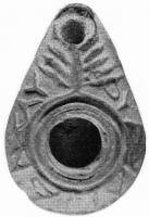 LMP-4176 - Lampe syro-palestinienne tardive (type pantoufle)terre cuiteLampe pantoufle avec inscription grecque sur l'épaule (Fos XY feni pasin IC). Au-dessus du bec, un motif en forme de menorah. Bec entouré d'un cercle en relief.