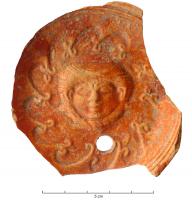 LMP-42143 - Médaillon : Gorgoneterre cuiteMédaillon de lampe représentant une tête de gorgone, de face, entourée d'une couronne végétale.