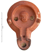LMP-4410 - Lampe de firme : Masque de théâtreterre cuiteLampe à bec en ogive et canal de bec, deux ou trois tenons sur l'épaule oblique et lisse ; disque orné d'un masque théâtral comique. Argile orange clair, engobe orange; base perdue. 