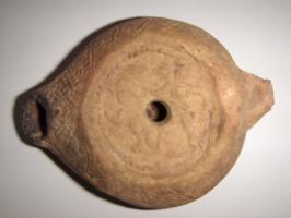 LMP-5100 - Lampe grenouille tardive Chasseterre cuiteLampe ovoïdale. Disque décoré d'un homme chassant un lion vers la gauche. Bec en goutte saillant du réservoir. Argile noisette, engobe beige-orangé.