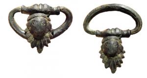 PAT-4053 - PatèrebronzePatère pourvue à l'opposé du manche d'une anse mobile, montée sur une applique brasée représentant un tête juvénile au-dessus d'une palmette.