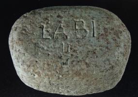 PDS-4476 - Poids en section de cône sur ellipse : 2 libraepierreTPQ : -100 - TAQ : -30Poids façonné en pierre, en forme de tronc sur base ellipsoïdale, à parois obliques ou convexes ; valeur gravée en chiffres romains, indiquant la masse en livres.