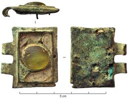 PLB-5146 - Plaque-boucle articuléebronzeTPQ : 450 - TAQ : 500Plaque-boucle rectangulaire, comportant un cabochon central ovale incrusté d'une pierre ou d'une verroterie.