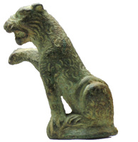 STE-4172 - Statuette zoomorphe : lion assisbronzeLion assis, gueule ouverte ; la patte droite relevée était sans doute posée sur un objet ; le corps est couvert d'incisions en arcs de cercles suggérant le pelage.