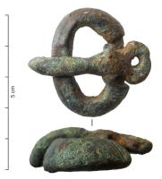 BCC-5016 - Ardillon de plaque-bouclebronze, ferArdillon scutiforme, forme étroite mais massive, généralement coulé sur une attache en fer qui peut parfois ressortir sur la face supérieure comme un rivet ; alliage au plomb, sans décor or simplement barré de traits incisés.