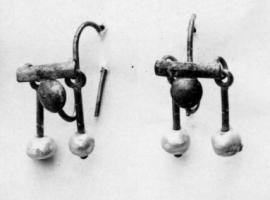 BCO-4027 - Boucle d'oreille à barretteor, pierreBoucle constituée d'une barrette transversale épaisse, reliée à l'arrière au fil recourbé en S, qui se suspend au lobe de l'oreille; la jonction est masquée par une pastille légèrement bombée; aux extrémités de la barrette, de petits segments de fils d'or articulés par des anneaux sont ornés de perles.