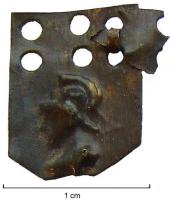 CUS-4008 - Cuirasse à écailles (lorica squamata)bronzeCuirasse à écailles en forme d'écu (rectangle aux angles inférieurs abattus), percées de trois paires de trous verticales dans la partie supérieure, et ornées d'un motif estampé : tête casquée a gauche, de Mars ou Minerve. Les écailles étaient attachées entre elles par des agrafes en bronze, formant des lignes continues, probablement cousues par les trous médians sur un support textile.