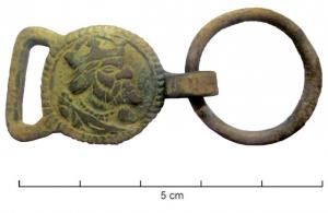 DMC-9021 - Attache de demi-ceintbronzeAttache en forme de plaque avec une bélière latérale et un autre anneau articulé de l'autre côté. L'attache en forme de plaque circulaire porte une tête de roi couronné, barbu (Charles Quint ?), vers la droite.