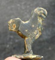 EPG-4425 - ÉpinglebronzeEpingle comportant au sommet une figurine schématique de coq, posée sur une collerette circulaire.