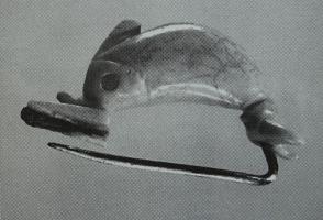 FIB-3018 - Fibule à corps de dauphinbronze, osFibule dont l'arc, sculpté  en os, figure le corpus arqué d'un dauphin dont le bec forme une gouttière de porte-ardillon; une aiguille en alliage cuivreux fixée sous la queue complète le dispositif.