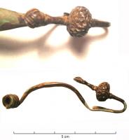FIB-3556 - Fibule laténienne à pied redressébronzeFibule à arc foliacé, ressort long ; le pied redressé vers l'arc est équipé à son extrémité d'un lourd bouton en sphère aplatie, décoré ; le bouton terminal est également décoré d'incisions.