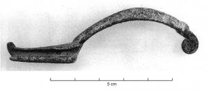 FIB-3954 - Fibule à ressort unilatéralbronzeFibule à arc tendu, de section semi-ovalaire ; ressort unilatéral, rapporté dans le prolongement de l'arc. Porde-ardillon étiré en gouttière, pied légèrement redressé.