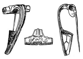 FIB-41227 - Fibule à arc non interrompu : ATEXTOSbronzeTPQ : 10 - TAQ : 70Arc tendu, coudé et épaissi à la tête, à bords parallèles, orné d'une côte centrale et de deux latérales (décor parfois absent) ; ressort protégé ; porte-ardilon trapézoïdal, ajouré ou fenestré. A la tête, décor caractéristique (fleuron ?) encadré de deux crosses en relief.