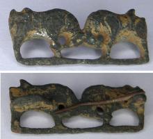 FIB-41500 - Fibule zoomorphe, groupe : taureaux affrontésbronzeBroche représentant deux taureaux affrontés, tête baissée; les queues retombent sur le dos; sur les corps, traits incrustés de nielle; barre de sol.
