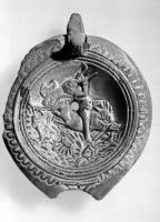 LMP-41303 - Lampe Loeschcke V : Eros sur dauphinterre cuiteLampe à bec court à volutes. Médaillon décoré d'un Eros jouant de la double flûte sur un dauphin. 