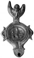 LMP-41890 - Lampe : Isis, Harpocrate, Hermès-Anubisterre cuiteLampe à anse fomant un grand réflecteur à relief (buste masculin barbu sur un croissant) ; sur le médaillon, Isis, Harpocrate et Hermès-Anubis.