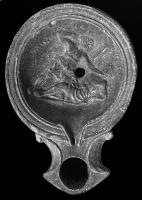 LMP-42674 - Lampe Loeschcke I : Pugilistes (?)terre cuiteLampe moulée, sans anse, épaule creusée de trois sillons concentriques, bec en enclume accosté de volutes ; décor du médaillon : deux hommes s'affrontant, l'un domine l'autre, tombé au sol, et s'apprête à lui donner un coup de poing. Au-dessus des deux personnages (pugilistes ?), légendes indiquant sans doute leurs noms.