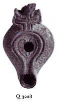 LMP-6048 - Lampe byzantine Croixterre cuiteLampe à bec long à canal; corps massif; épaule ornée de traits centripètes en relief; anse plastique en forme de croix. Médaillon décoré d'un motif linéaire cordiforme.