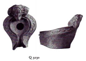 LMP-6049 - Lampe byzantine Tête animaleterre cuiteLampe à bec long à canal; corps massif; anse plastique en forme de tête animale. Médaillon vierge; épaule ornée de demi-oves.
