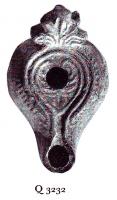 LMP-6051 - Lampe byzantine Palmette terre cuiteLampe à bec long à canal; corps massif; anse plastique en forme de palmette ou fleur de lys. Médaillon décoré d'un motif linéaire cordiforme; épaule ornée de traits centripètes.