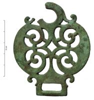 MRS-4038 - Applique latérale de morsbronzeApplique circulaire ajourée, ornée de motif ajourés formant deux peltes adossées autour d'un vide central losangique, donc destiné au canon du mors; deux bélières opposées, l'une circulaire et l'autre rectangulaire.