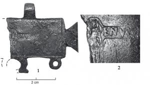 PDH-4175 - Pendant de harnais en tabula ansatabronzePendant en forme de tabula ansata, avec suspensions sommitales centrées et trois anneaux à la base pour y suspendre des pendants. La surface porte une estampille centrée, répartie de part et d'autre d'un motif figuré également estampé.