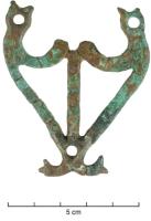 ANS-5001 - Attache d'anse de seau lyriforme à terminaisons zoomorphesbronzeTôle découpée à plat en forme de lyre. Elle peut être fixée à un seau par plusieurs clous. Les quatre extrémités supérieures et inférieures sont terminées par une tête animale à gueule ouverte, dont l’œil est figuré par une ocelle pour les extrémités inférieures et une perforation circulaire pour les extrémités supérieures. Ces ocelles peuvent également orner l'intégralité de l'objet.