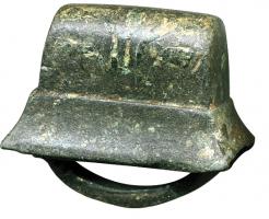 APJ-4003 - Applique de jougbronzeTPQ : 50 - TAQ : 150Applique de joug, entièrement en bronze, dont la base, équipée d'une forte bélière coulée, épouse la forme de l'arête du joug sur laquelle l'objet était fixé ; le sommet massif, en forme de dôme rectiligne, est orné d'incrustations niellées.