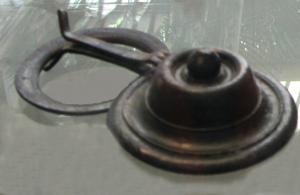 APM-4085 - Applique de meublebronzeApplique circulaire, simplement ornée de moulures concentriques en fort relief, avec un bouton sommital ; revers creux sans autre mode de fixation que la fente sommitale dans le bord de l'objet, sur laquelle est parfois conservée un crampon replié sur lui-même. Le crampon sert parfois à fixer aussi un anneau articulé qui encadre le médaillon.