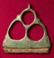 BRI-4002 - Briquetbronze, ferBriquet plat, constitué d'une lame de fer sur laquelle est coulée une poignée en bronze, formée de trois anneaux disposés en triangle.