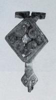 FIB-4376 - Fibule émailléebronzeTPQ : 100 - TAQ : 300Fibule à corps losangique, creusé de plusieurs loges d'émail (4 cercles, ou 4 pétales et écoinçons autour d'une petite étoile centrale elle aussi émaillée, ou plusieurs logettes triangulaires); le pied se termine par une une tête de reptile.