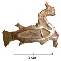 FIB-4634 - Fibule zoomorphe : capricornebronzeFibule en forme de chèvre marine, stylisée, nageant à droite; le corps est creusé de trois loges d'émail.