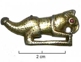 FIB-5287 - Fibule zoomorphe : animal imaginaireargent doréPetite fibule en argent doré représentant un animal imaginaire de profil, à bec crochu, oreille pointue. L'oeil est une perle de verre rouge. Il a une queue large avec une terminaison arrondie et rayée. Toute la surface de son corps est couverte de pointes. Une
ligne de sol relie les pattes. Sur le revers, le ressort en fer de l'ardillon est conservé des deux côtés de la bélière venue de fonderie, en dessous de l'arrière train de l'animal. Le porte-ardillon est placé en dessous du cou.