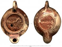 LMP-41797 - Lampe à bec rond limité par un trait : Oiseau sur rameau, L M ADIECterre cuiteMoulée, anse verticale percée à deux sillons sur la tranche. Réservoir circulaire à profil biconvexe. Bandeau penché vers l'extérieur. Disque en cuvette limitée par deux sillons concentriques. Décor : oiseau à droite, ailes relevées, posé sur un rameau feuillu. Bec arrondi limité par un trait droit ponctué aux extrémités. Base circulaire plate en léger relief limitée par un sillon, estampillée L M ADIEC. Engobe rouge à brun sur toute la lampe.