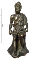 STE-4362 - Statuette : Héphaïstos - Vulcain assisbronzeTPQ : 1 - TAQ : 250Homme barbu, coifé d'un pilos et d'une tunique dégageant l'épaule droite (exomis), assis sur un bloc indistinct, portant deux outils de forgeron (pince et marteau).