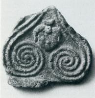 ANT-4030 - Antéfixe : tête et spiralesterre cuiteAntéfixe moulée, avec en façade deux motifs spiralés, adossés de part et d'autre d'une tête humaine juvénile surmontée dun croissant (Luna?) ; palmette au-dessus (à la base, parfois, marque du fabricant).