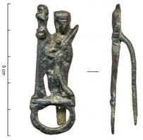 CLA-9012 - ClavendierbronzeClavendier représentant Sainte-Barbe de profil, appuyée sur un long bâton (?), la palme de martyre dans la main gauche; au dos de la figurine, une pince pour maintenir l'accessoire à la ceinture ; en dessous, un anneau dans lequel passait une chaîne à laquelle on pouvait pendre divers ustensiles (ciseaux, clefs...). 