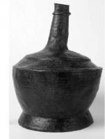 CRU-5013 - Cruche marteléebronzeCruche en tôle, panse trapue reposant sur une partie annulaire sertie pour former à la fois le fond et le pied ; carène marquée, épaule rythmée par des carènes et col cylindrique étroit.