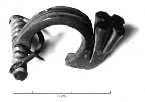 FIB-3575 - Fibule de type DuerobronzeFibule composite avec un arc coulé très massif, arc creusé de profonds sillons médians, avec un pied également massif, redressé et s'élargissant en fleuron à sommet plat ;  la tête de l'arc est percée pour recevoir un ressort long, sur axe et à corde interne.