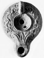 LMP-4088 - Lampe syro-palestinienne, [[DOA]]terre cuiteLampe à bec en ogive à volutes; disque nu; épaule ornée de feuilles et pampres de vigne; sur le début du bec, une palmette; anse non percée. Inscription sur la base : [[DOA]].