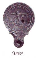 LMP-41059 - Lampe Loeschcke IV : Ménadeterre cuiteLampe à bec à volutes. Médaillon orné d'une Ménade marchant vers la gauche, portant un tambourin (tympanon) et un thyrse sur l'épaule.