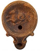 LMP-4316 - Lampe Loeschcke IV : Monstre marin, BRIterre cuiteLampe à bec à ogive et volutes latérales; disque orné d'un monstre marin, mi-poisson, mi-cheval vers la gauche. Argile noisette, engobe marron foncé; base plate entourée d'un anneau en relief; au centre, marque LRI en lettres incisées.