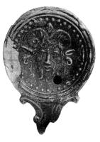 LMP-4869 - Lampe Loeschcke IV : Jupiter-Ammon terre cuiteLampe ronde à long bec en ogive à volutes. Médaillon décoré d'une tête de Jupiter Ammon (Zeus-Ammon).