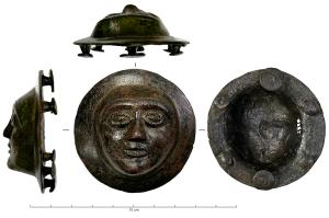 PHA-4042 - Phalère : visagebronzePhalère figurant un visage glabre, en demi-relief sur une couronne lisse, traits schématiques, yeux bordés d'un cordon guilloché ; au revers, six fixations pour un harnais de cuir.
