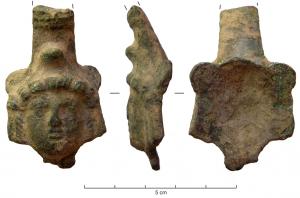 CRU-4034 - CruchebronzeCruche à anse plate, attache d'anse ornée d'une tête d'Attis dont le bonnet phrygien forme un ergot au-dessus de la chevelure encadrant le visage.